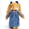 Pop in bio katoen en wol met blauwe ogen en 2 blonde staartjes. Ze staat recht en draagt een gestreepte T-shirt met lange mouwen en een blauwe overal jurk.