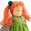 Close up sur la tête d'une poupée de chiffon Nanchen Wolke  aux cheveux roux montés en deux queues avec ruban verts, ayant des yeux bleus, un sweat rayé multicolore et une chasuble en velours vert.