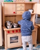A child plays in a play kitchen in solid wood with cabinets