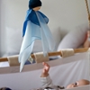 Poupée Nanchen en soie bleue suspendue au dessus d'un berceau. Le bébé la regarde.