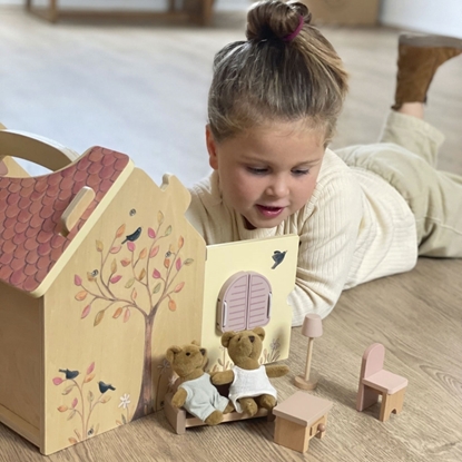 A little girl plays with the bears and their furniture inside and outside the wooden dollhouse.